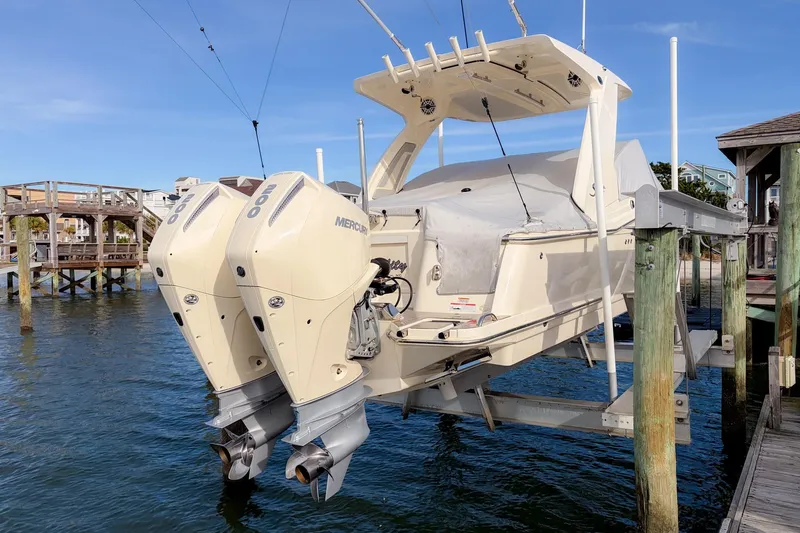 Slide: The Image of 2023 Scout 277 Dorado boat with dual Mercury engines on a lift by the dock. - 26