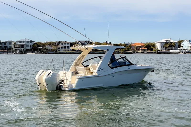 Slide: The Image of 2023 Scout 277 Dorado boat cruising on a calm waterway near waterfront homes. - 3