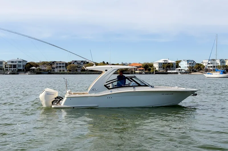Slide: The Image of 2023 Scout 277 Dorado boat cruising on a calm waterway near waterfront homes. - 4
