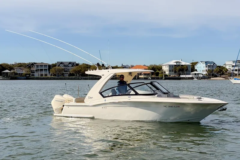 Slide: The Image of 2023 Scout 277 Dorado boat cruising on a calm waterway near coastal homes. - 5
