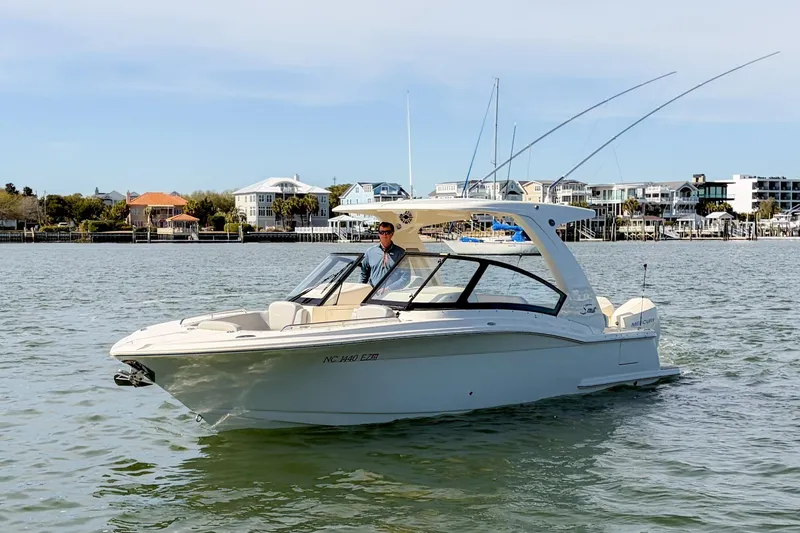 Slide: The Image of 2023 Scout 277 Dorado boat cruising on a calm waterfront with scenic background. - 6