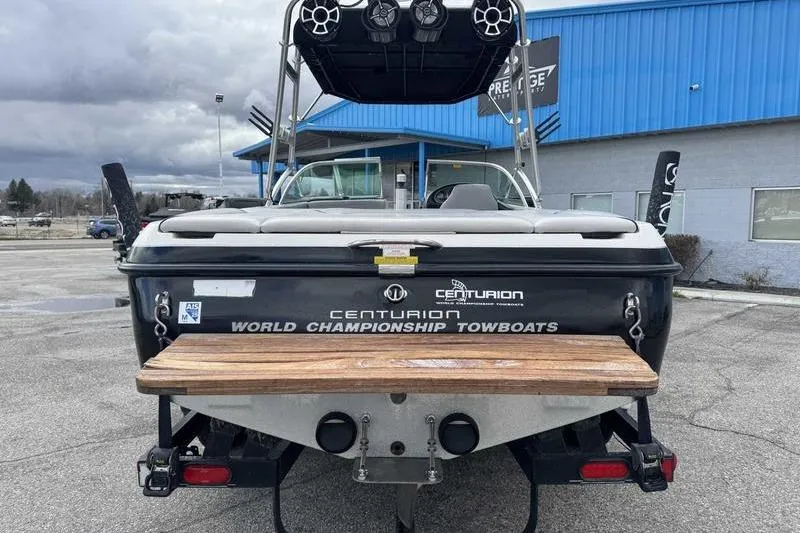 Slide: The Image of 2005 Centurion Elite V-Drive boat, rear view, parked near blue building. - 3