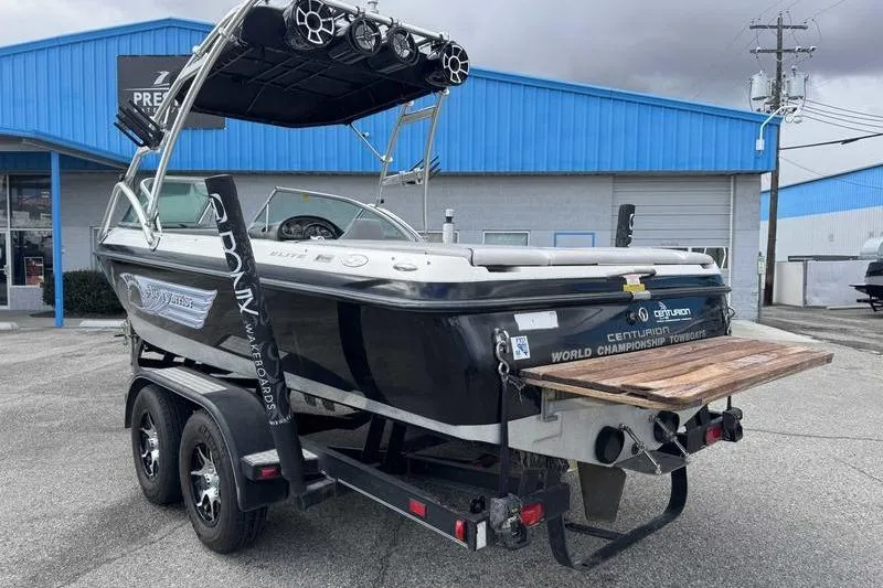 Slide: The Image of 2005 Centurion Elite V-Drive boat on trailer, parked outside blue building. - 5