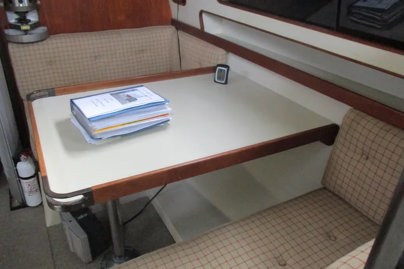 Slide: The Image of 1981 C & C 32 sailboat interior with table, cushioned seating, and documents. - 34