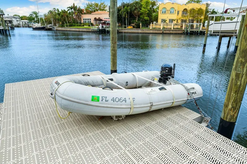 Slide: The Image of Inflatable dinghy docked on a marina with waterfront homes in the background. - 53
