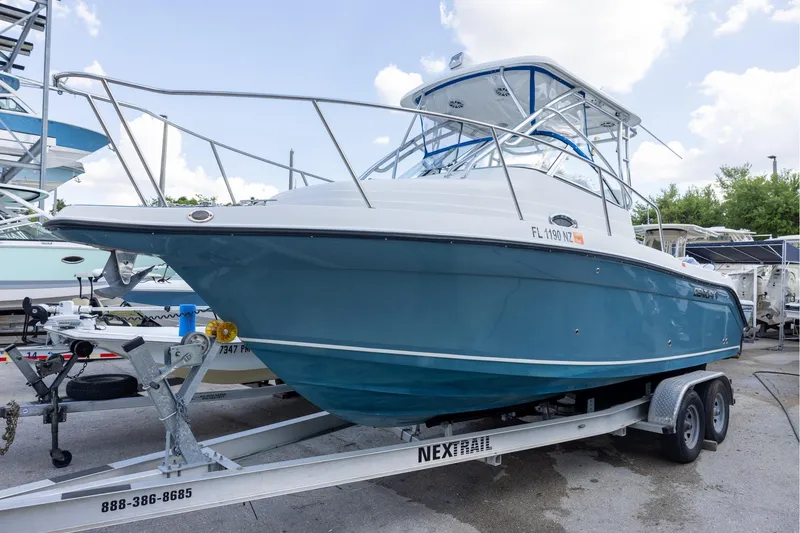 The Image of 2008 Century 2400 Walk-Around boat on trailer, blue hull, parked outdoors. - 0