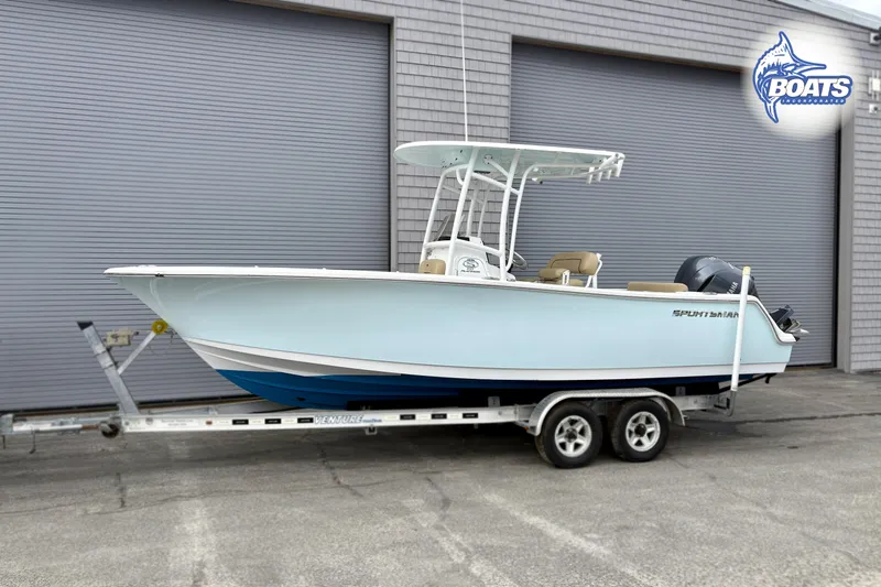 Slide: The Image of 2019 Sportsman Open 232 Center Console boat on trailer, parked near a gray building. - 1