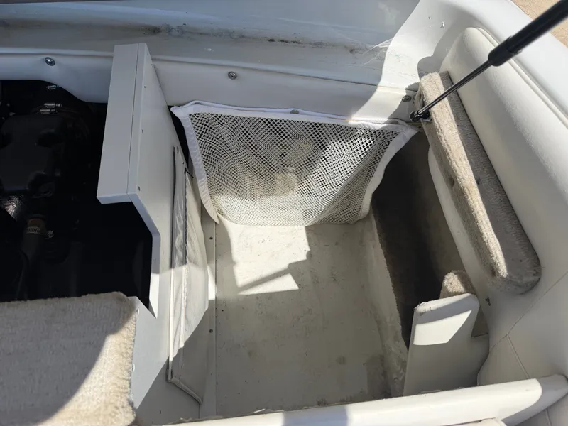 Slide: The Image of The image shows the interior of a 2002 Crownline 202 BR boat with storage and carpeted flooring. - 16
