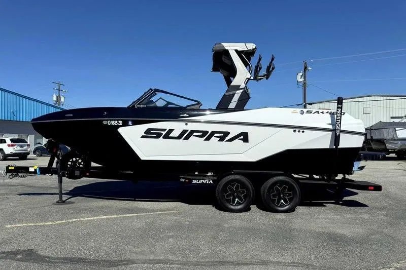 The Image of 2025 Supra SA boat on trailer, black and white design, parked outdoors. - 1