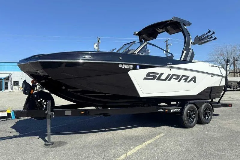 Slide: The Image of 2025 Supra SA boat on trailer, black and white design, parked outdoors. - 4