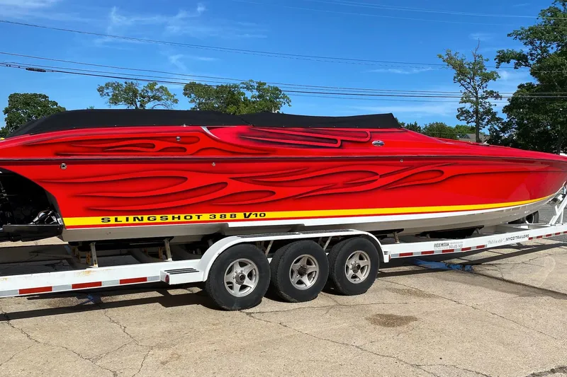 The Image of Red 2005 Hustler 388 SLINGSHOT boat with flame design on trailer. - 1