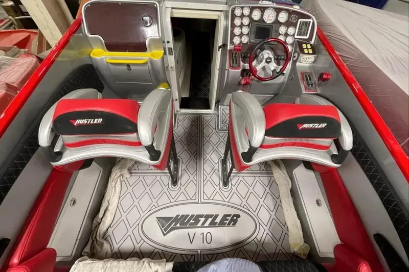 Slide: The Image of 2005 Hustler 388 SLINGSHOT boat interior with red and gray seating, dashboard, and controls. - 16