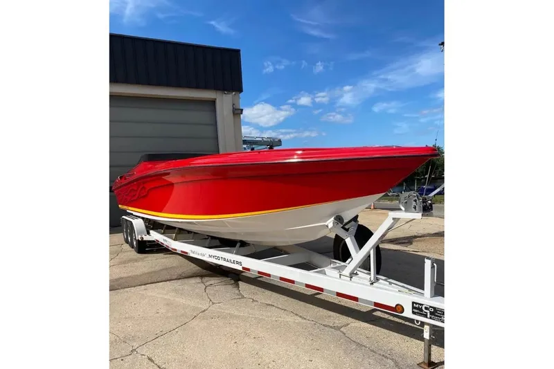Slide: The Image of Red 2005 Hustler 388 SLINGSHOT boat on trailer, parked outdoors under blue sky. - 3