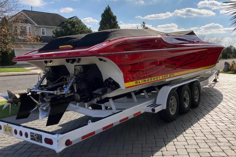Slide: The Image of Red 2005 Hustler 388 SLINGSHOT boat on trailer, parked in residential driveway. - 4