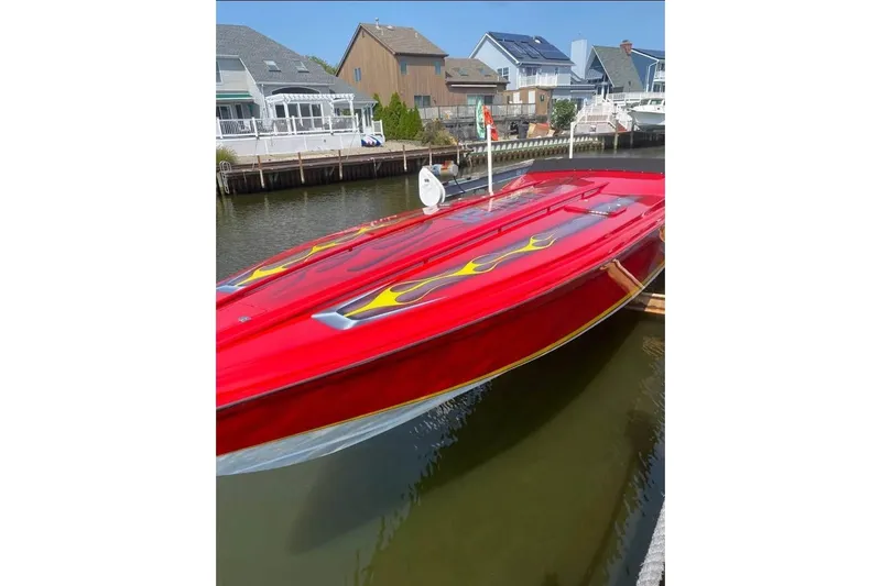 Slide: The Image of Red 2005 Hustler 388 SLINGSHOT speedboat with flame decals docked near waterfront homes. - 9