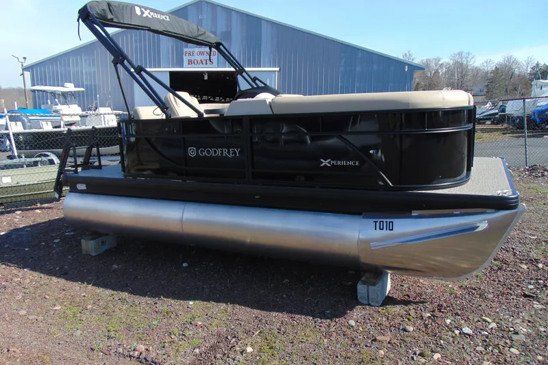 The Image of 2026 Godfrey EX 1680 CX pontoon boat displayed outdoors near a warehouse. - 2