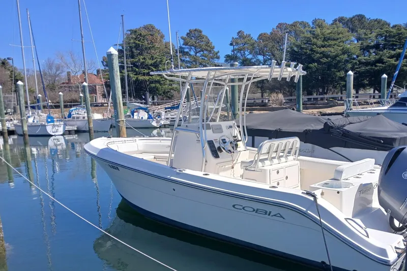 The Image of 2021 Cobia 237 Center Console boat docked in a marina with sailboats. - 1