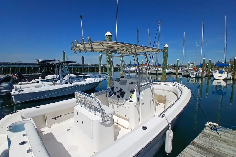 Slide: The Image of 2021 Cobia 237 Center Console boat docked at a marina with clear blue skies. - 11