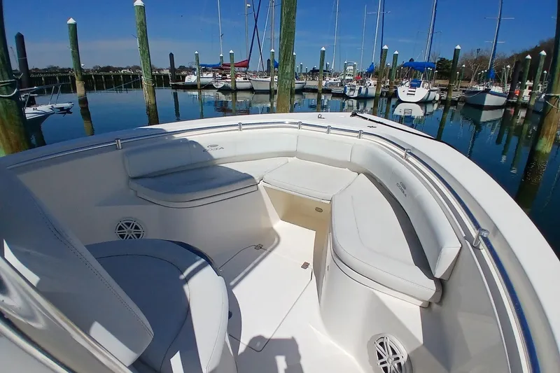 Slide: The Image of 2021 Cobia 237 Center Console boat interior at marina, featuring spacious seating and clear blue skies. - 12