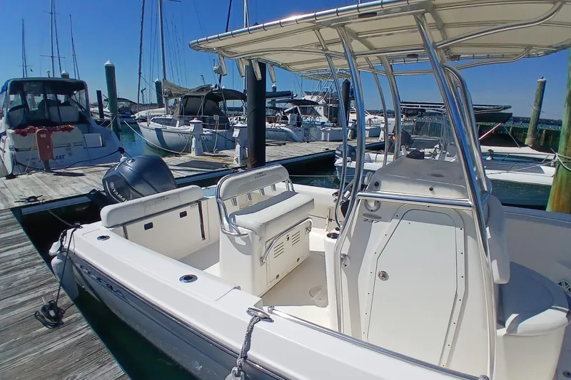Slide: The Image of 2021 Cobia 237 Center Console boat docked at a marina with other vessels. - 8