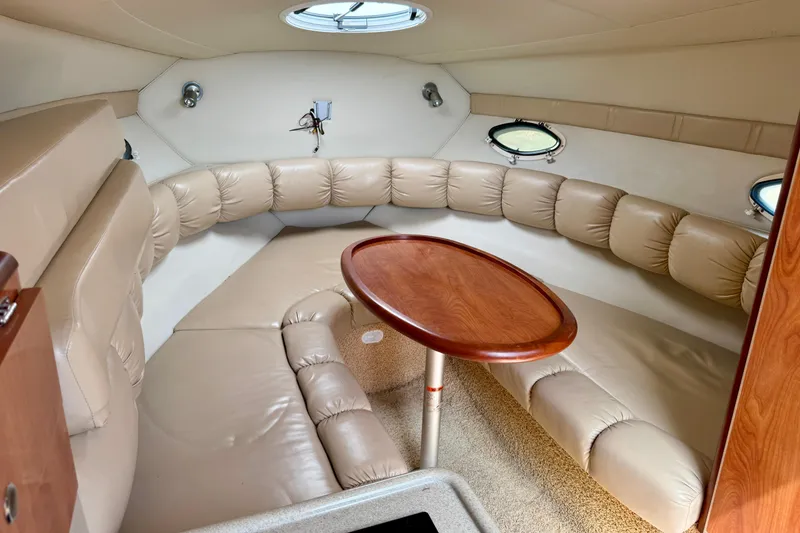 Slide: The Image of Interior of 2007 Larson Cabrio 274 boat with beige seating and wooden table. - 10
