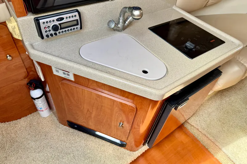 Slide: The Image of 2007 Larson Cabrio 274 boat interior with kitchenette, sink, stove, and wooden cabinetry. - 12