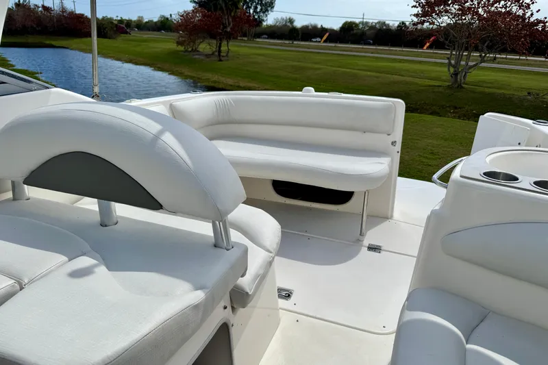 Slide: The Image of 2007 Larson Cabrio 274 boat interior with white seating and cup holders by a lake. - 19