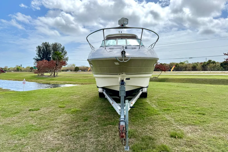 Slide: The Image of 2007 Larson Cabrio 274 boat on trailer, parked on grassy area near a pond. - 2