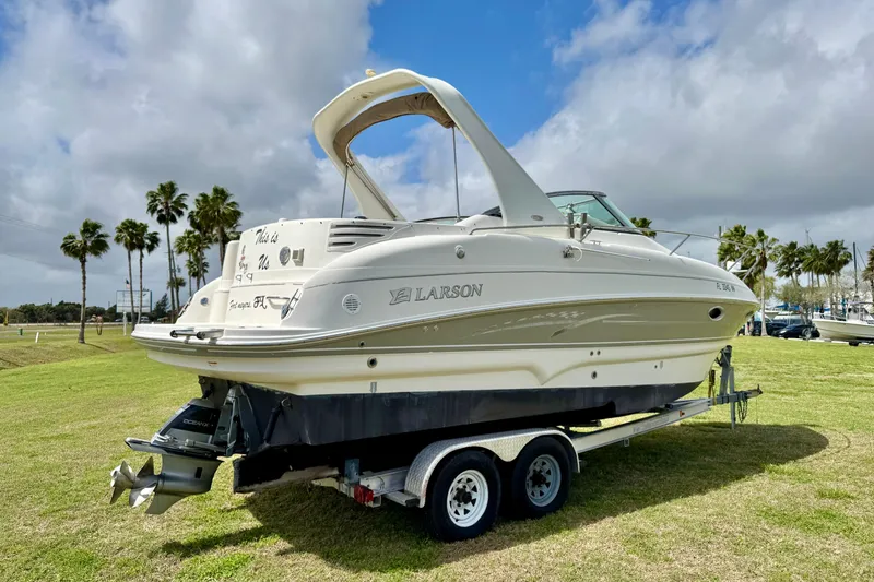 Slide: The Image of 2007 Larson Cabrio 274 boat on trailer, parked on grassy area with palm trees. - 25