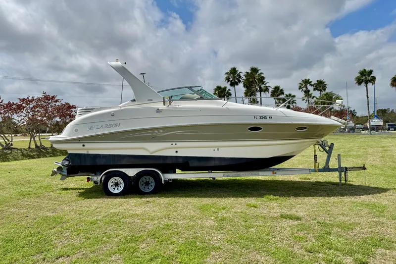 Slide: The Image of 2007 Larson Cabrio 274 boat on trailer, parked on grassy field under cloudy sky. - 4