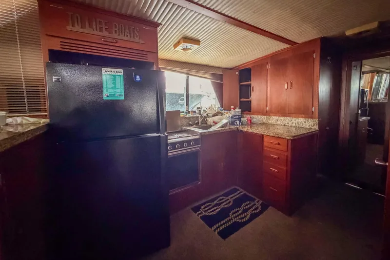 Slide: The Image of Kitchen area of 1984 Blue Water 51 Coastal boat with wooden cabinets and appliances. - 25