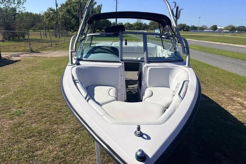 Slide: The Image of 2005 Nautique Super Air Nautique 210 boat with open bow seating, parked on grass. - 12