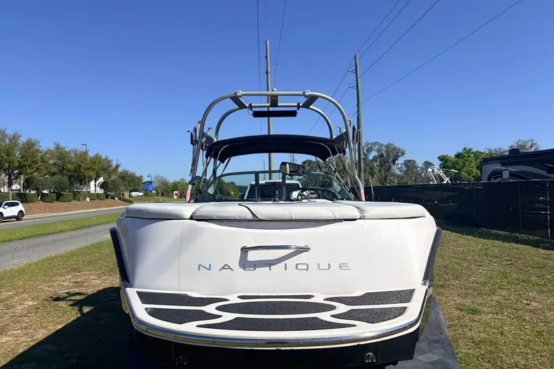 Slide: The Image of 2005 Nautique Super Air Nautique 210 boat, rear view, parked on grass under clear blue sky. - 14