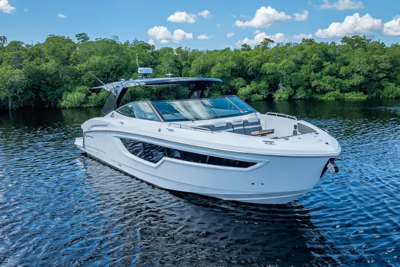 Slide: The Image of 2022 Cruisers Yachts 38 GLS OB on serene water with lush greenery backdrop. - 19