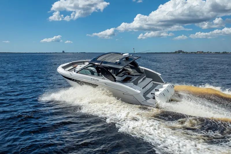 Slide: The Image of 2022 Cruisers Yachts 38 GLS OB speeding on open water under a partly cloudy sky. - 2