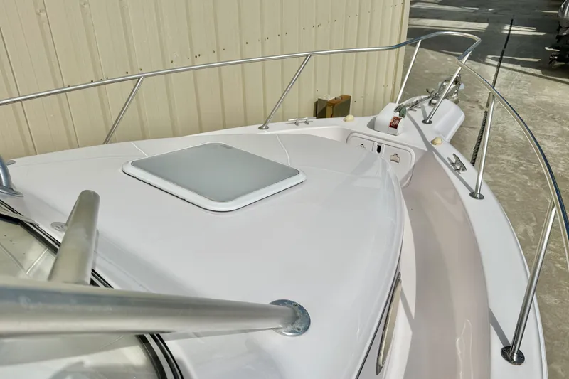 Slide: The Image of 2005 Pro-Line 29 Walkaround boat deck with railing and hatch, docked near a building. - 24