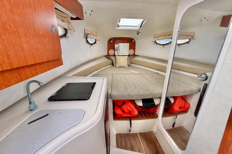 Slide: The Image of 2005 Pro-Line 29 Walkaround cabin interior with bed, kitchenette, and storage. - 29