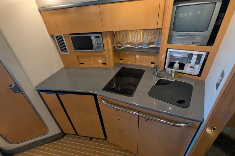 Slide: The Image of Compact kitchen area in a 2004 Maxum 3700 SY yacht with appliances and sink. - 24