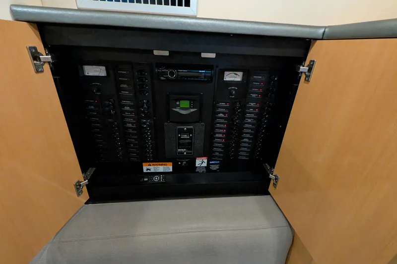 Slide: The Image of Electrical panel inside a 2004 Maxum 3700 SY boat, with open wooden cabinet doors. - 39
