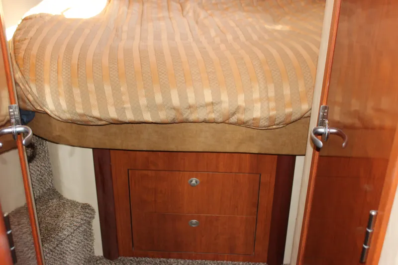 Slide: The Image of Interior cabin of 2006 Sea Ray 40 Sundancer with striped bedding and wooden storage. - 33