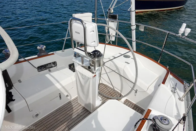 Slide: The Image of Cockpit of 1993 Alden 43 Aft, featuring steering wheel and seating, on calm water. - 15