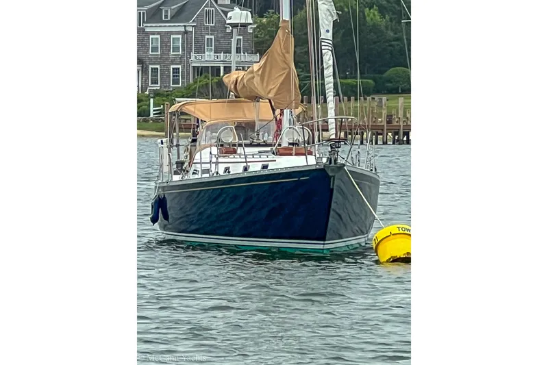 Slide: The Image of Sailboat Alden 43 Aft Cockpit, 1993 model, anchored near a coastal home. - 2