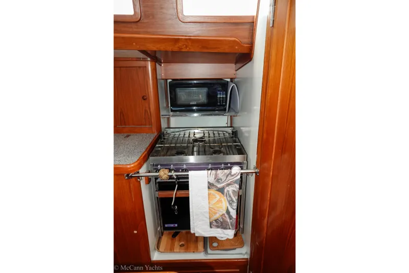 Slide: The Image of Compact yacht kitchen with stove, microwave, and wooden cabinetry in a 1993 Alden 43 Aft Cockpit. - 52