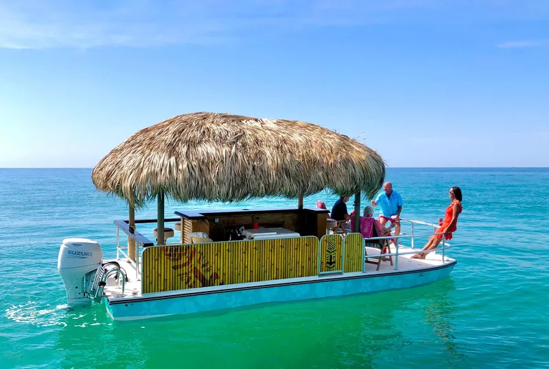 Slide: The Image of Beachcat 23 Catamaran 2023 with tiki hut, people relaxing on turquoise ocean. - 2