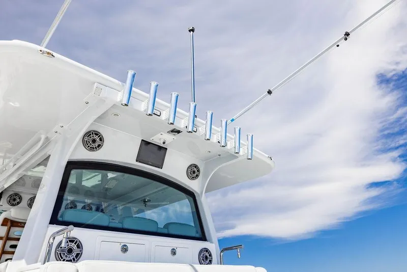 Slide: The Image of 2023 HCB 53 Suenos boat with rod holders against a blue sky background. - 36