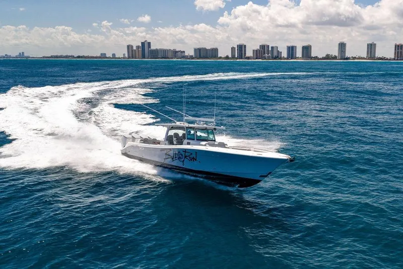 Slide: The Image of 2023 HCB 53 Suenos boat cruising on blue ocean with city skyline in background. - 6