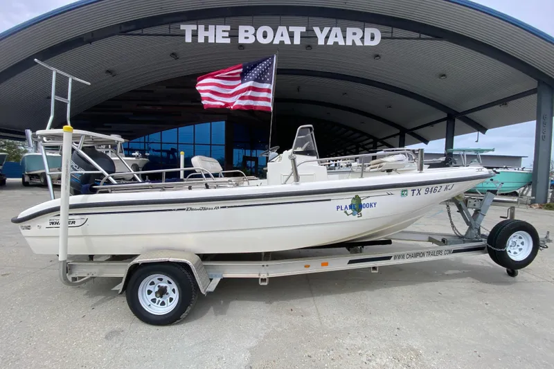 Slide: The Image of 2000 Boston Whaler Dauntless 18 boat on trailer at The Boat Yard, American flag displayed. - 2