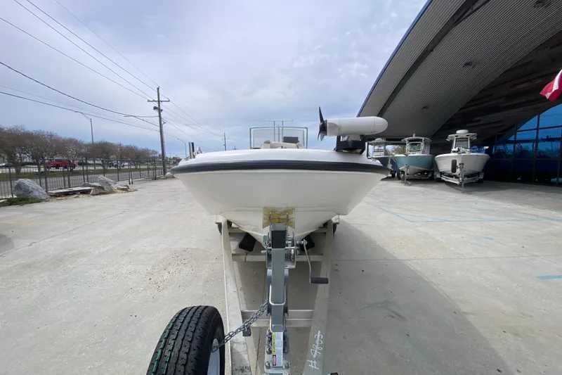 Slide: The Image of 2000 Boston Whaler Dauntless 18 boat on trailer, parked outdoors near a modern building. - 8