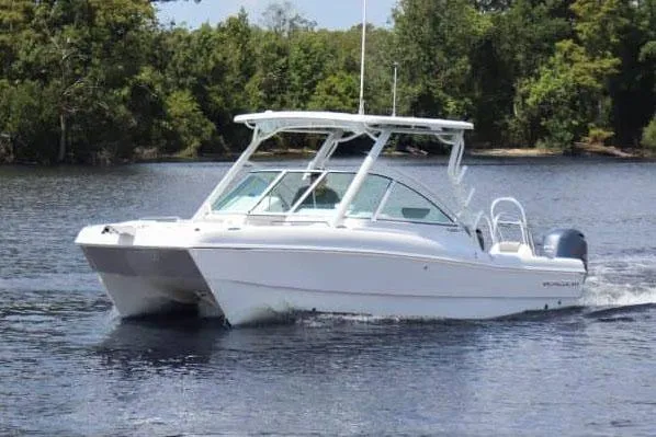 The Image of Manufacturer Provided Image: 2026 World Cat 230 DC boat cruising on a calm lake with lush green trees. - 0