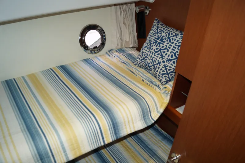 Slide: The Image of Cozy cabin interior of 2014 Beneteau Swift Trawler 34 with striped bedding and porthole. - 12